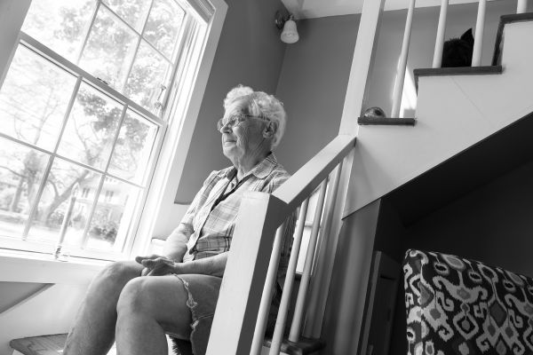 Woman sitting on stairs, looking out window.