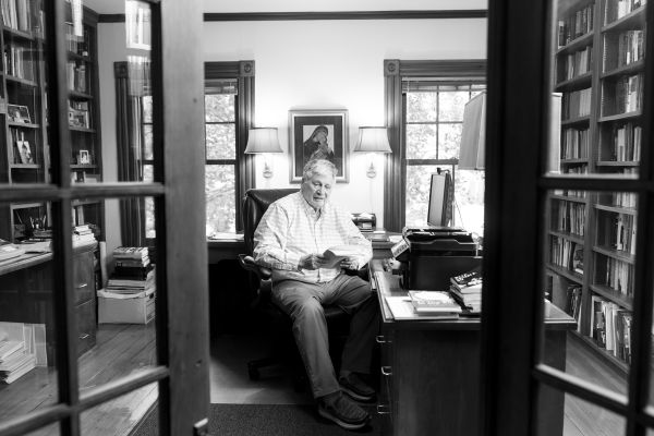 Looking through glass doors at man seated at desk in library.