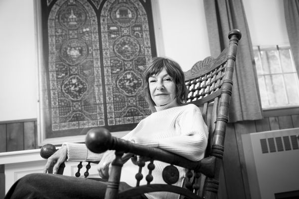 Woman seated in rocking chair in front of mural.